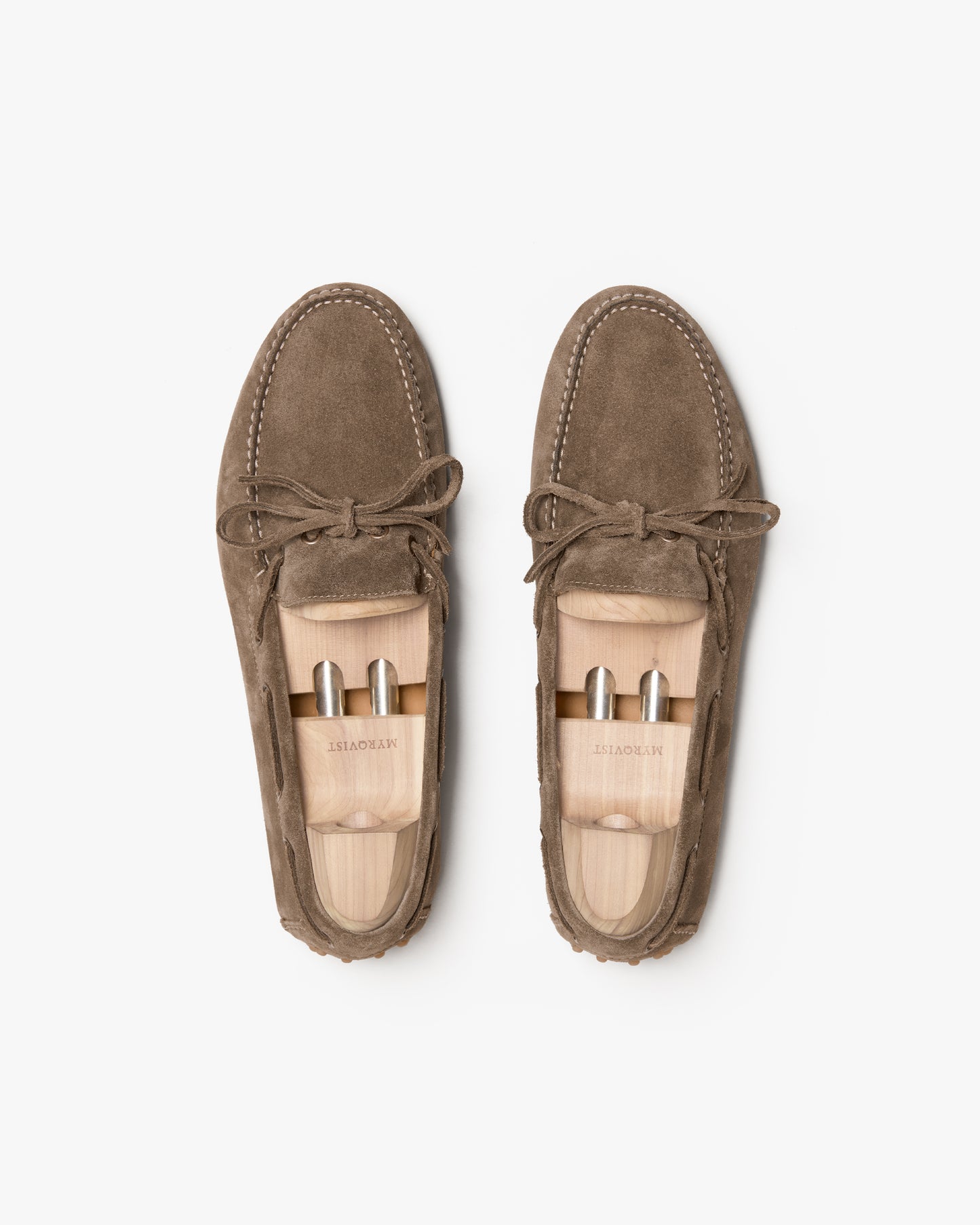 A pair of Tofta – Taupe Suede driving shoes with wooden shoe trees on a white background.