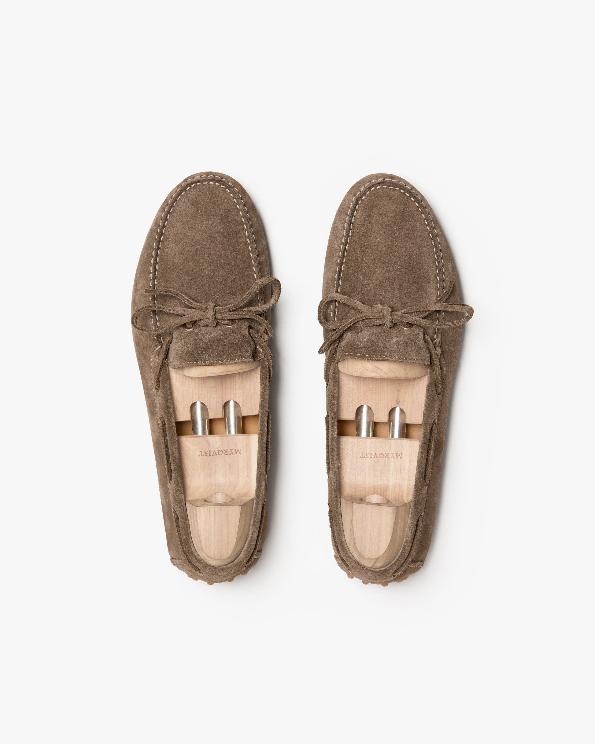 A pair of Tofta – Taupe Suede driving shoes with wooden shoe trees on a white background.