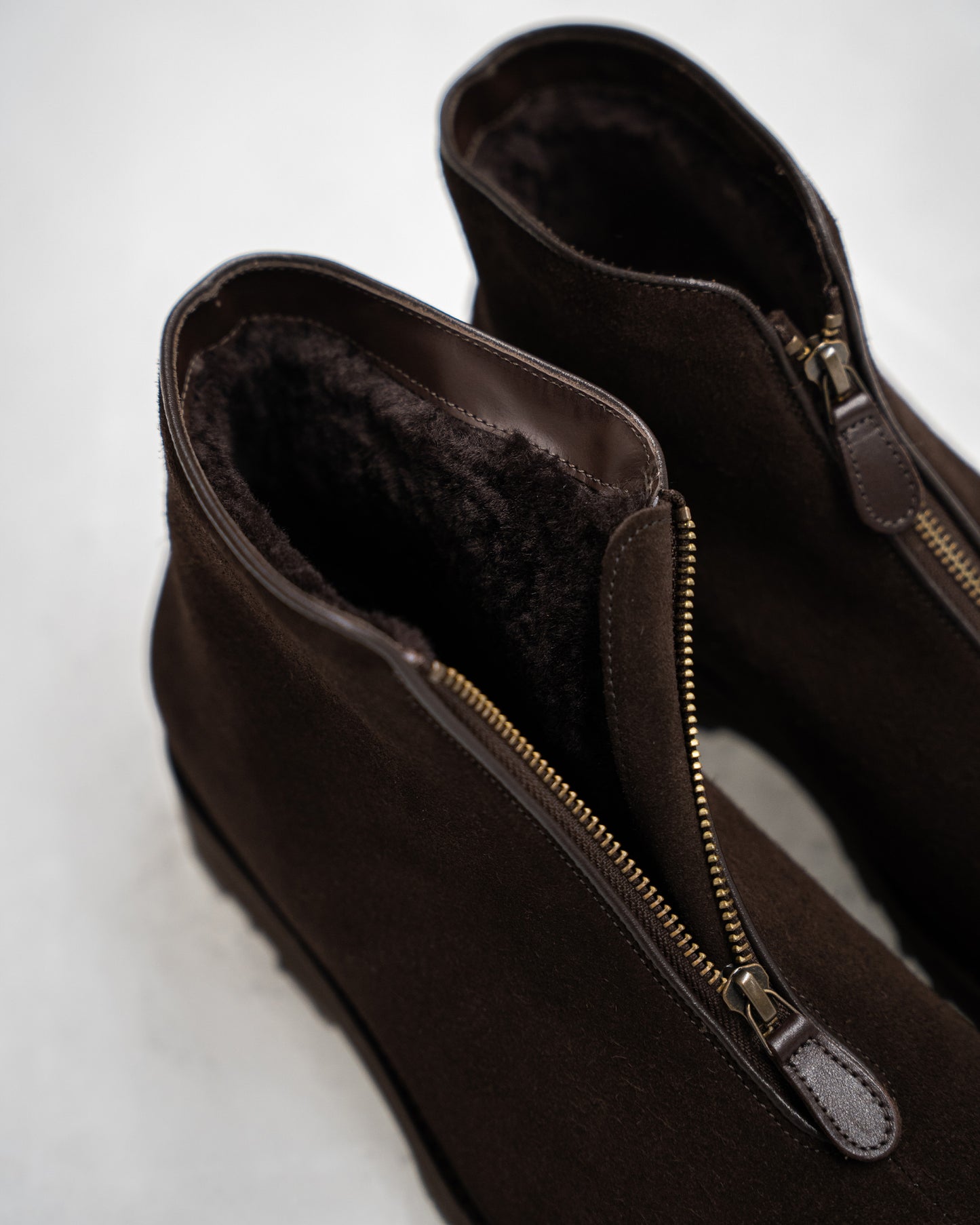 Detail view of Funäs in dark brown suede, highlighting the plush shearling lining, central zipper with leather pull, and soft suede exterior designed for warmth and comfort in winter.