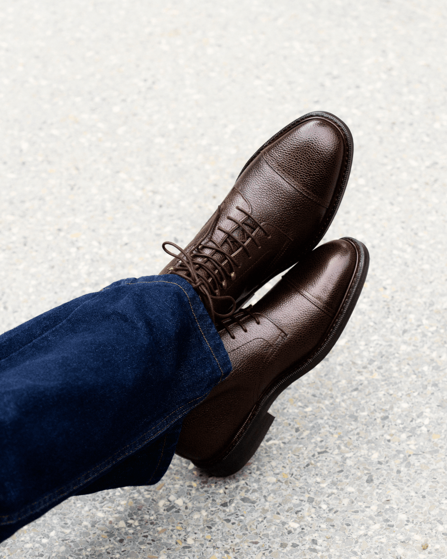 Close-up on a person wearing Abisko – Dark Brown Country Calf boots with dark blue jeans, seen from above.