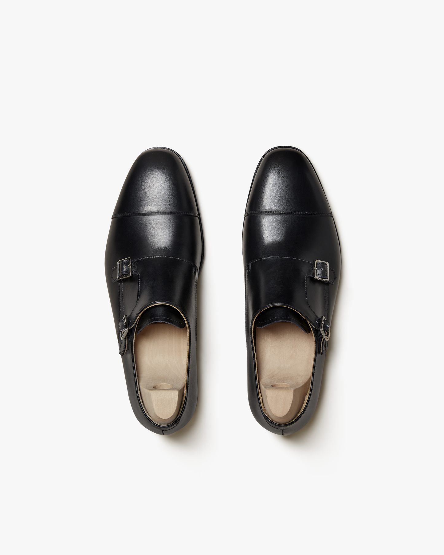 A pair of Ålsten – Black Calf double monk strap shoes with shoe trees, pictured from above on a white background.