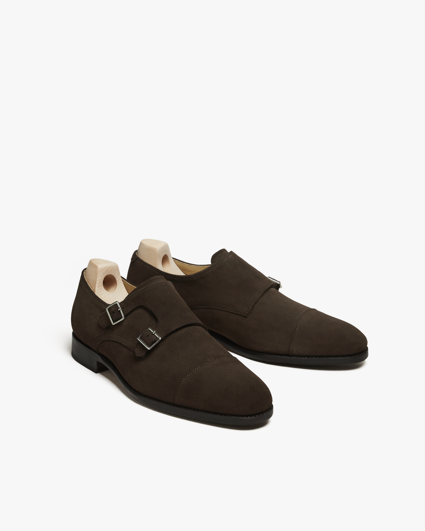 A pair of Ålsten – Dark Brown Suede double monk strap shoes, shown with wooden shoe trees on a white background.