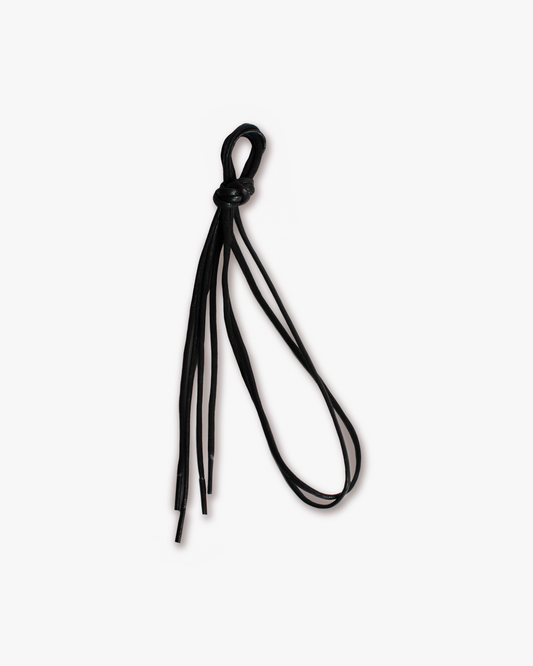 A pair of black waxed shoelaces, tied in a knot and shot against a clean white background.