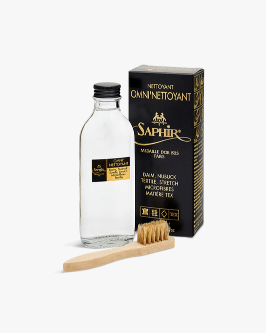 A bottle of Saphir – Suede Shampoo presented with its black and gold packaging and the included silk-bristled wooden brush.
