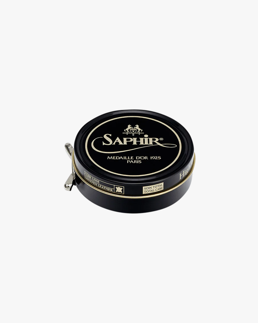 A tin of Saphir – Pâte de Luxe shoe wax in its signature black and gold packaging, set against a white background.
