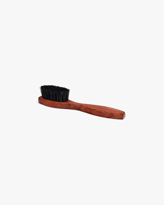 A side view of the Saphir – Application Brush, highlighting its dark boar bristles and waxed wooden handle.