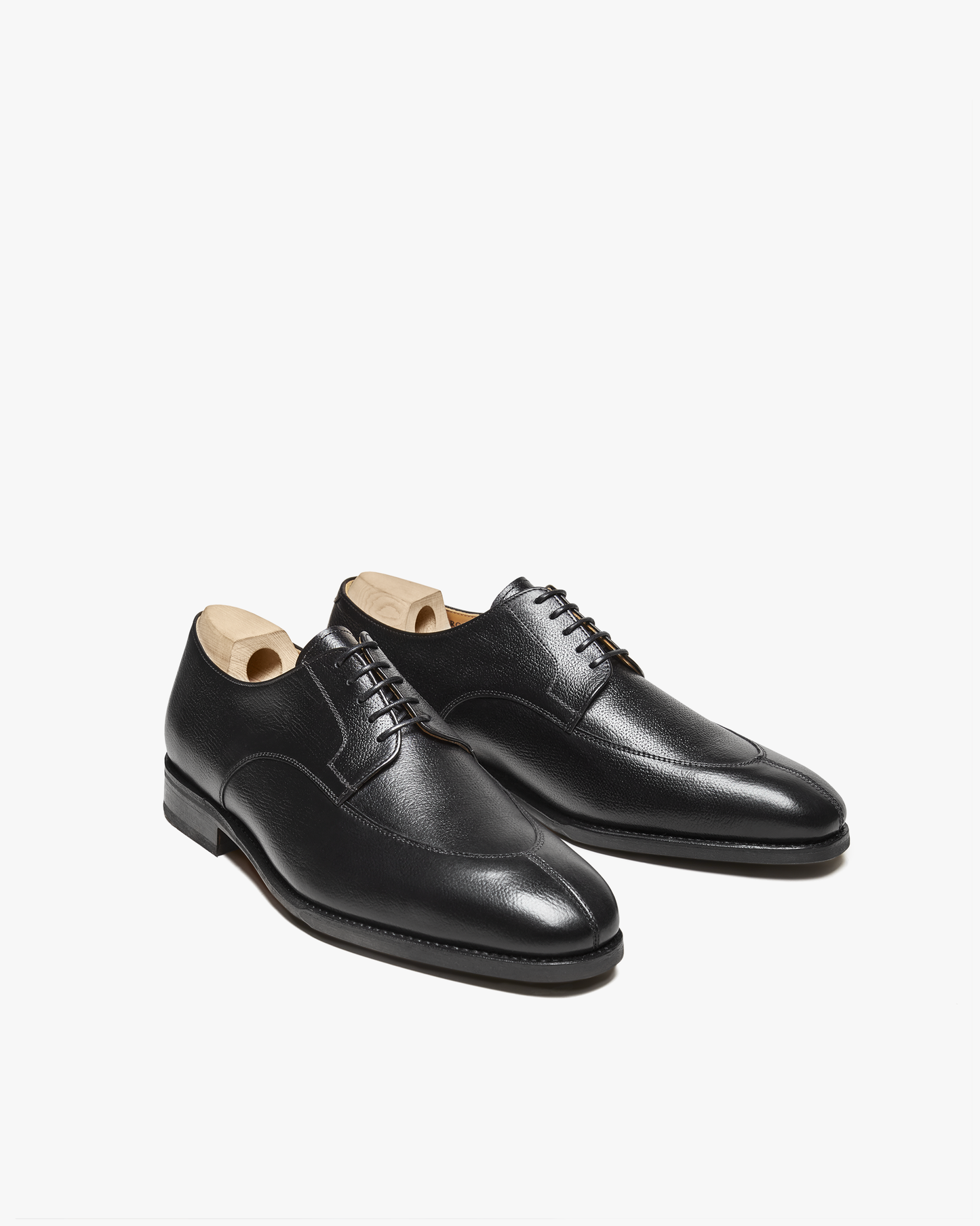 A pair of Norrmalm – Black Hatch Grain derby shoes with wooden shoe trees, shown from an angle on a white background.
