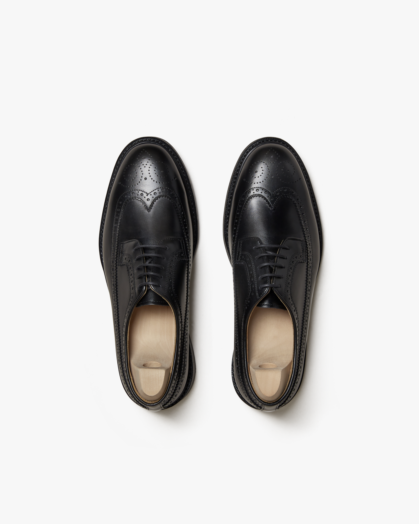 A pair of Orust – Black Calf long-wing derbies with wooden shoe trees, captured from above against a white background.