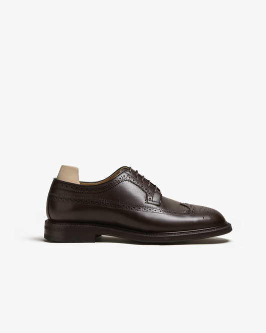 A side profile view of Orust – Dark Brown Calf, showcasing the long-wing design and intricate punching details.