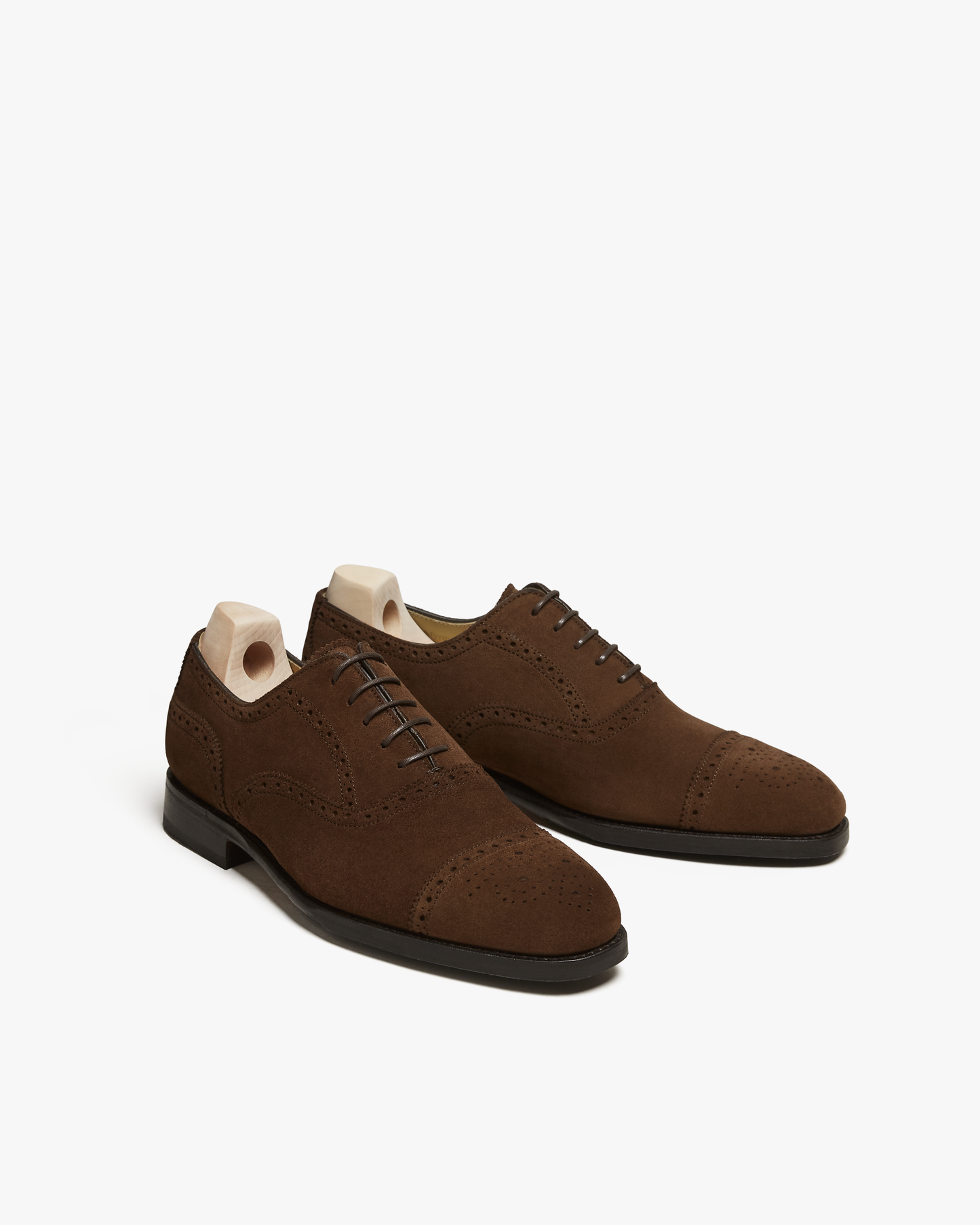 A pair of Strömsö – Polo Suede Oxford shoes with wooden shoe trees, pictured against a white background.
