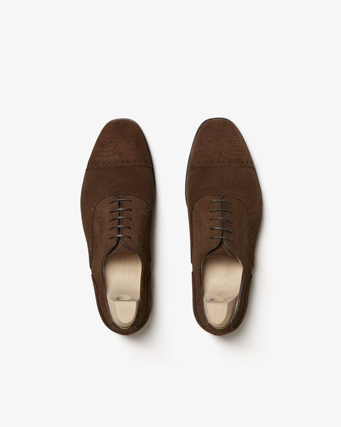 A top-down view of Strömsö – Polo Suede semi-brogue Oxfords with shoe trees, against a white background.