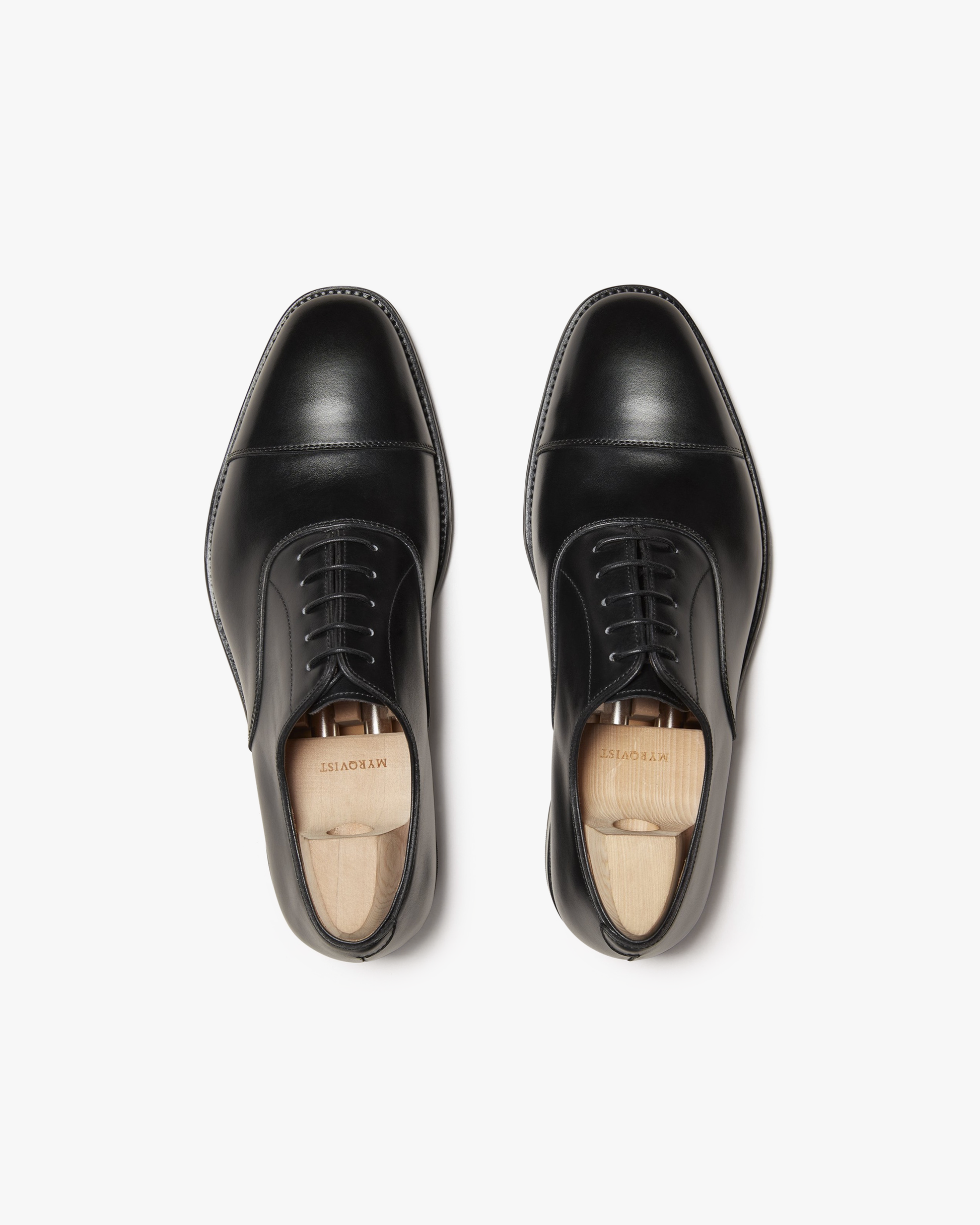 A top-down view of Vinterviken – Black Calf, a classic cap toe Oxford shoe shown with wooden shoe trees.
