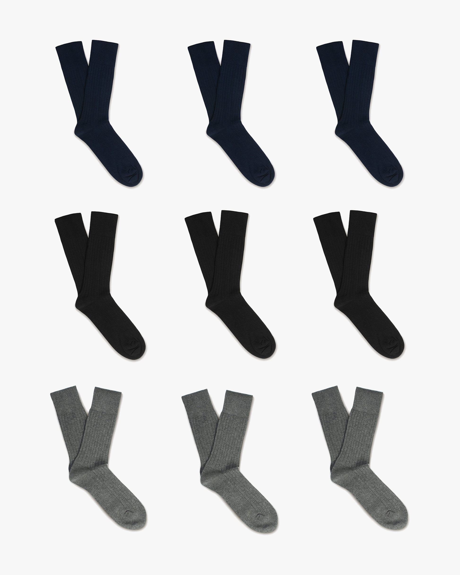 A flat lay of the Oscar – Cotton Socks 9-pack, featuring rows of navy, black, and grey ribbed socks on a white background.