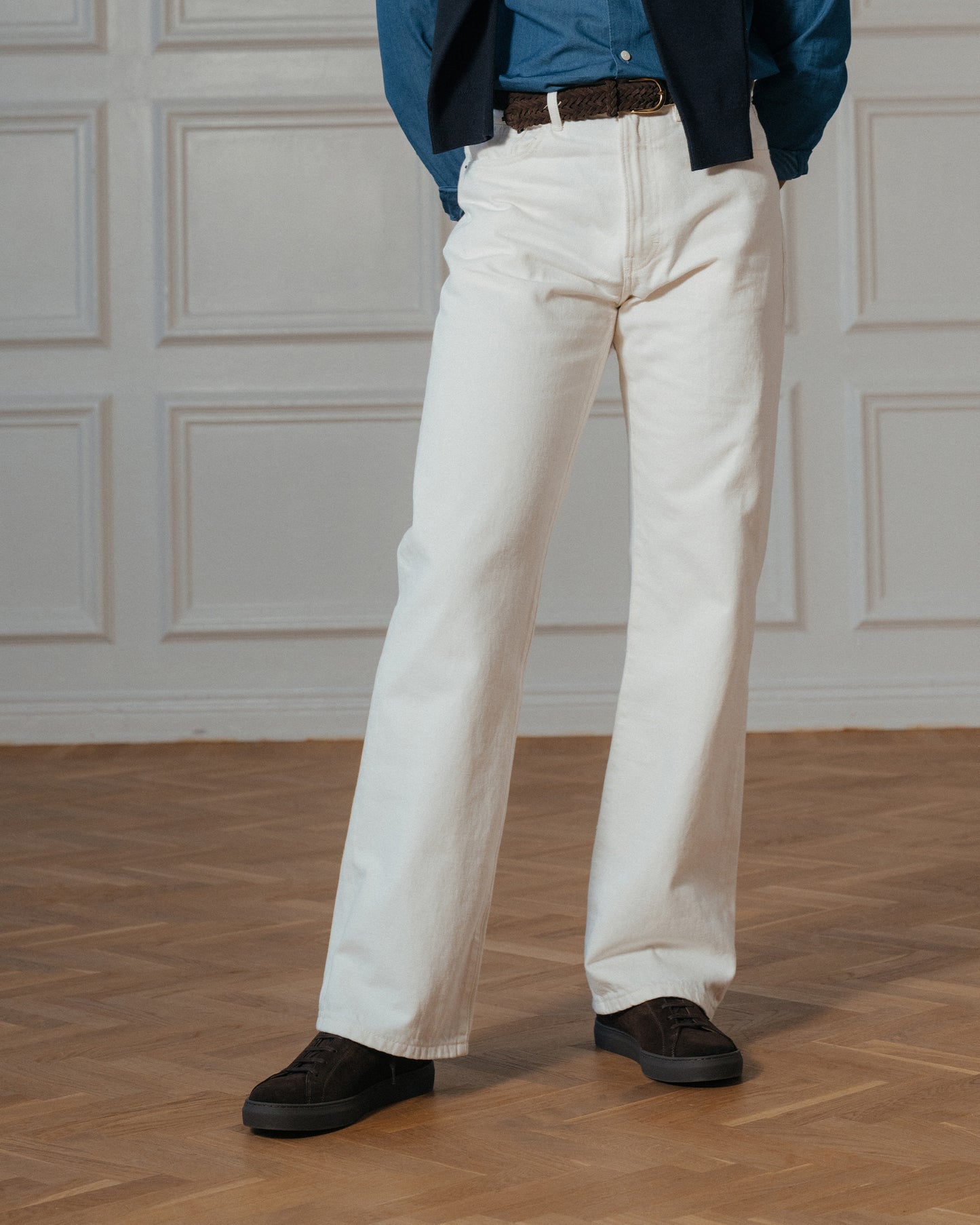 Oaxen Monochrome Sneaker aus dunkelbraunem Wildleder kombiniert mit heller Stoffhose, blauem Hemd und Sakko in elegantem Business-Casual-Outfit auf Holzboden.