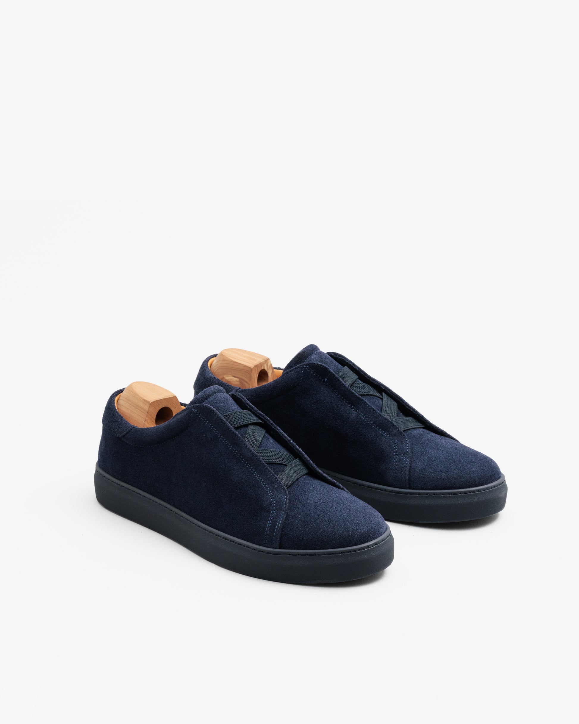 Alnö Monochrome II Slip-on-Sneaker aus mitternachtsblauem Wildleder mit Schuhspannern, Schrägansicht zeigt elastische Einsätze und monochrome Gummisohle.