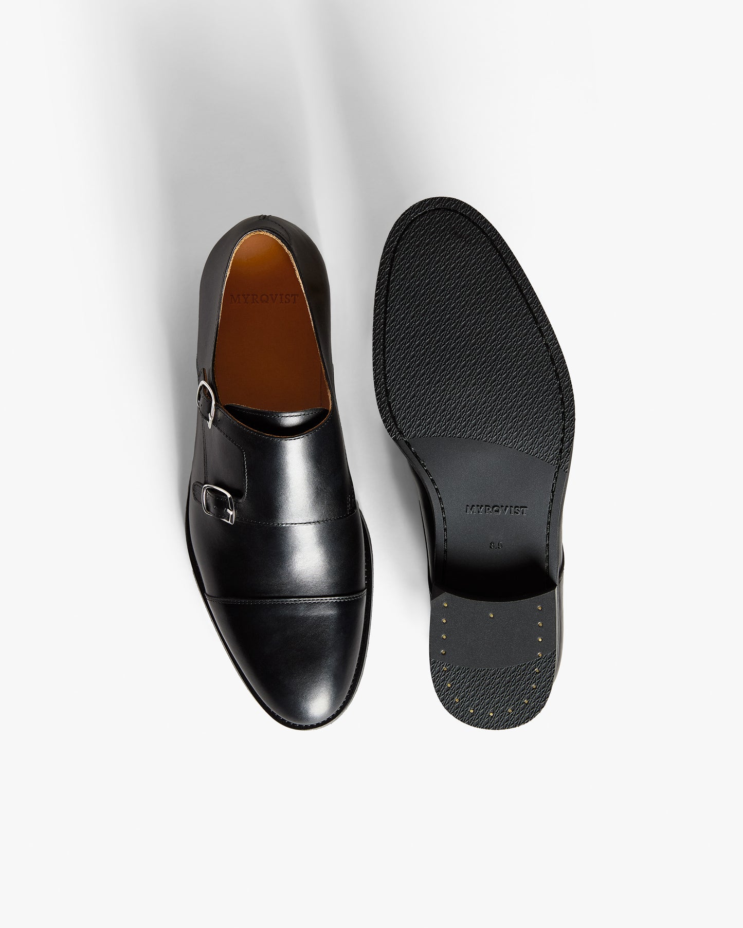 Ålsten II in black calf double monk strap shoe with dual buckles, shown upright next to a textured rubber sole.
