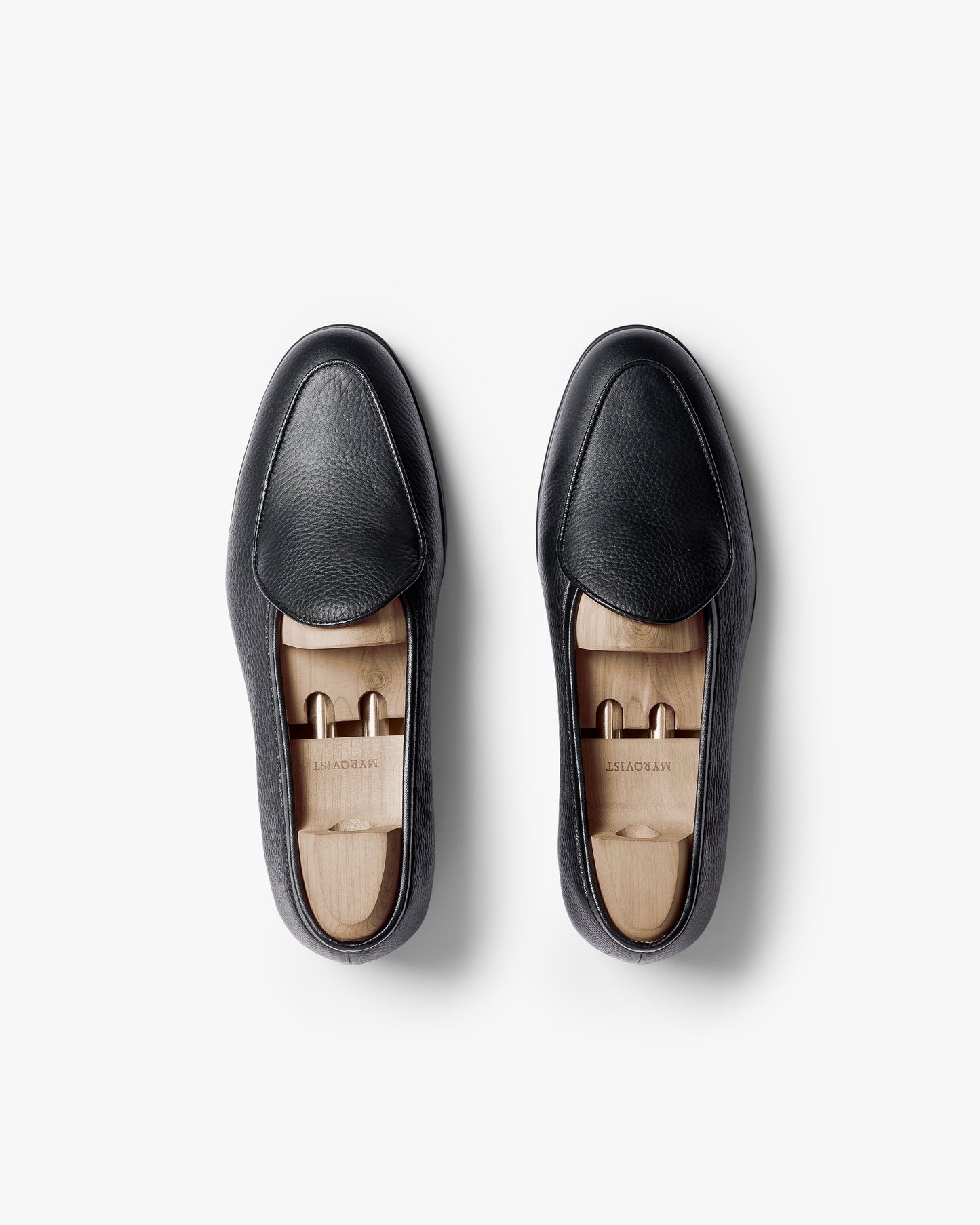 A top-down view of a pair of Ängby Walker – Black Grain Calf loafers with shoe trees inside, against a white background.