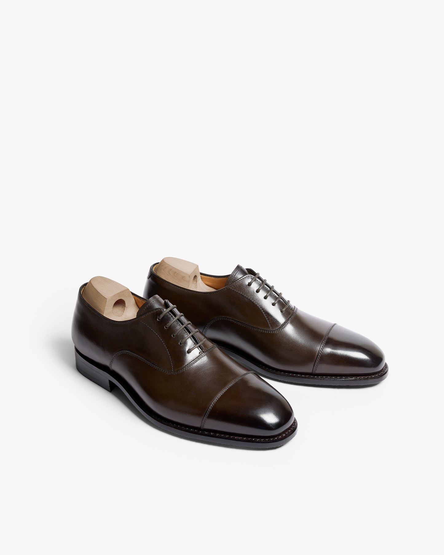 A pair of Äppelviken II – Dark Brown Calf oxford shoes with shoe trees inside, shown at an angle against a white background.