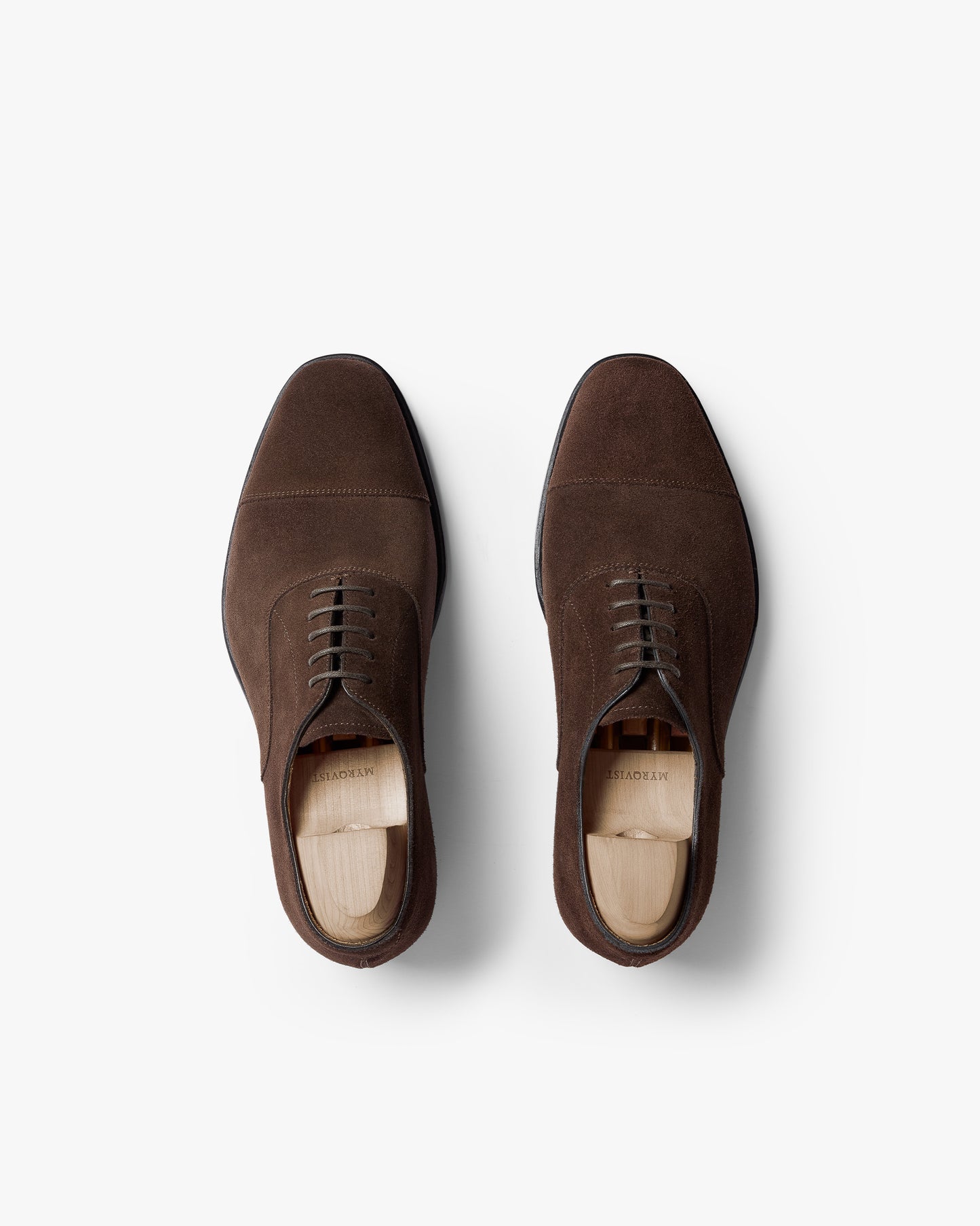 Top-down view of a pair of Äppelviken II – Dark Brown Suede oxford shoes with shoe trees inside, against a white background.