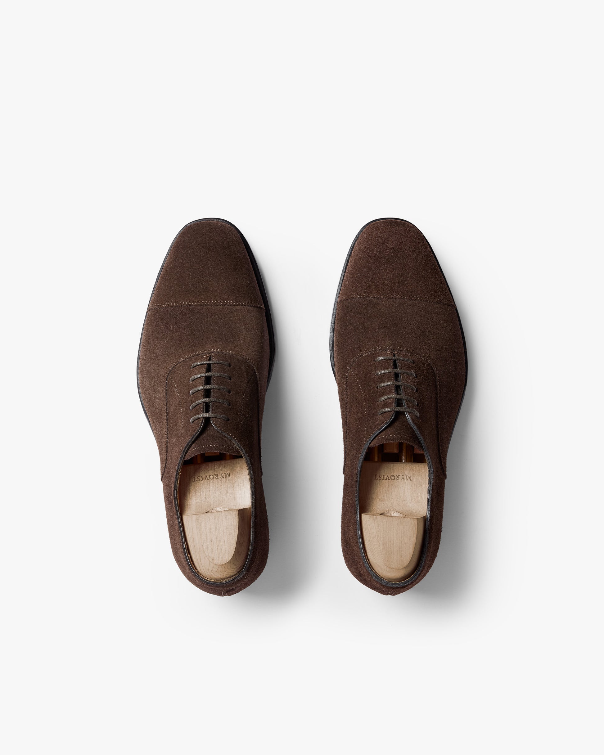 Top-down view of a pair of Äppelviken II – Dark Brown Suede oxford shoes with shoe trees inside, against a white background.