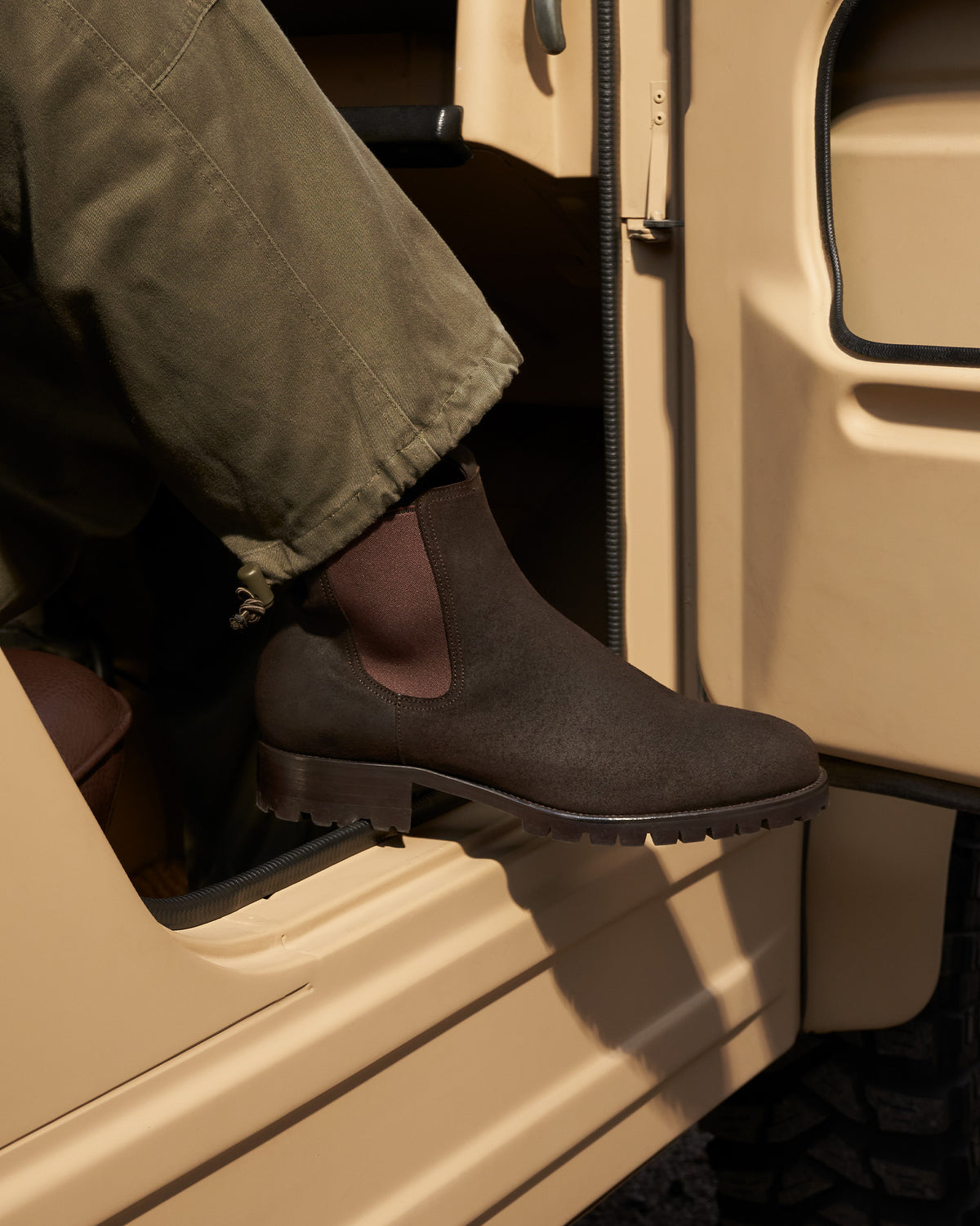Elfvik II – Brown Waxed Suede Chelsea boot worn with olive trousers exiting a vehicle, showing its rugged lug sole.