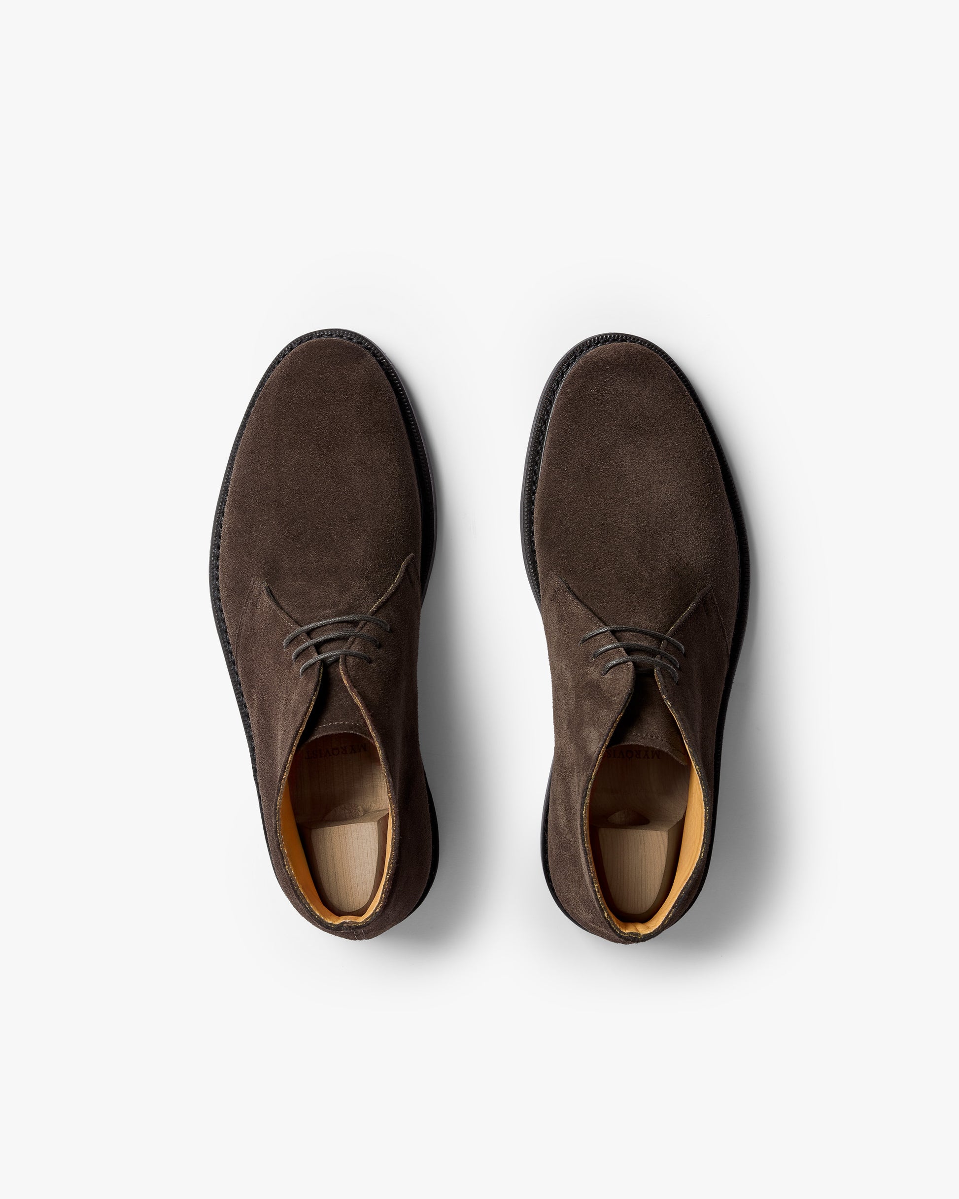 Top-down view of a pair of Gyllsjö II – Dark Brown Suede boots with shoe trees inside, set against a white background.