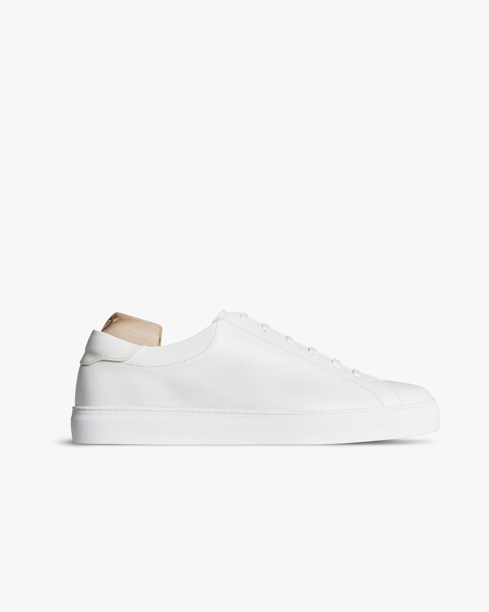 Oaxen in white calf leather with a low profile, shown with a wooden shoe tree against a white background.