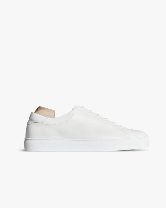 Oaxen in white calf leather with a low profile, shown with a wooden shoe tree against a white background.