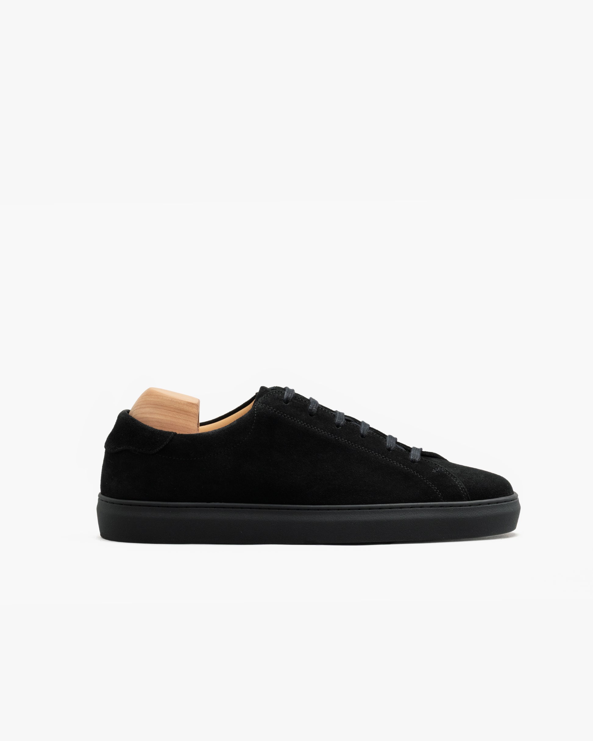 Oaxen Monochrome in black suede shown in profile, featuring a minimalist silhouette with tonal laces, a matte suede finish, and a color-matched sole, presented with a wooden shoe tree inside.
