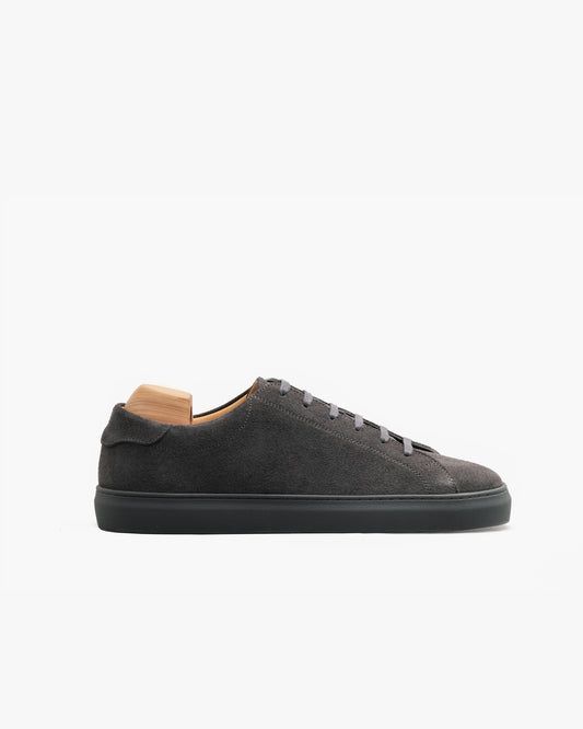 Low-top Oaxen Monochrome sneaker in dark grey suede with a matching sole and tonal laces, featuring a minimalist silhouette and soft, velvety texture, shown in a side profile on a white background.