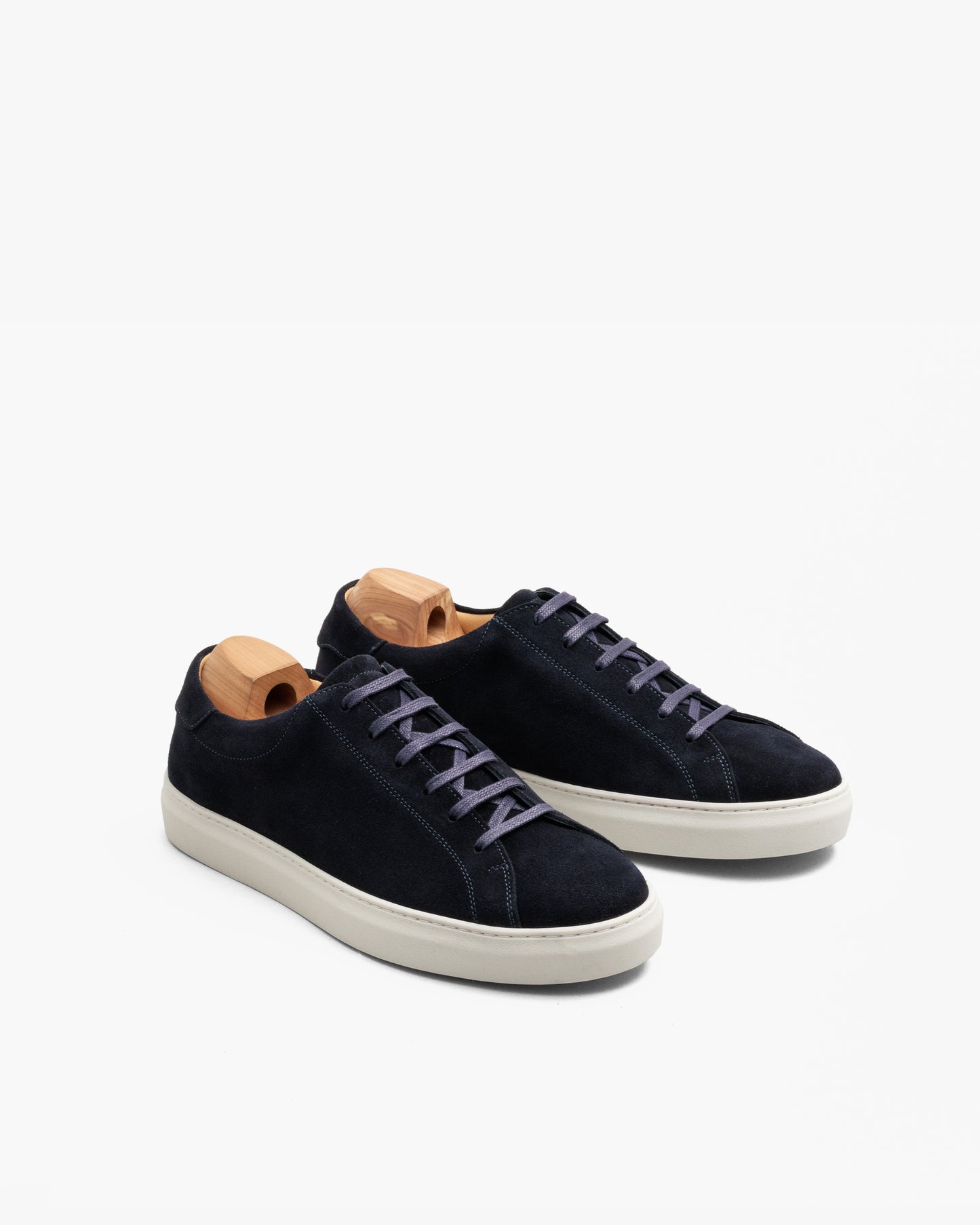 Oaxen in navy suede displayed at an angle, featuring deep blue suede uppers, flat cotton laces, tonal stitching, and off-white soles, each shoe fitted with a wooden shoe tree.
