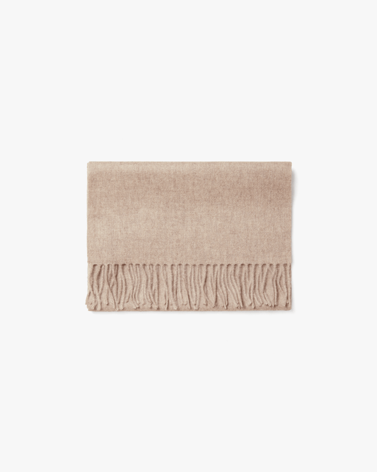 A studio shot of the Wool Scarf – Beige, folded to showcase its soft texture and fringed edge.