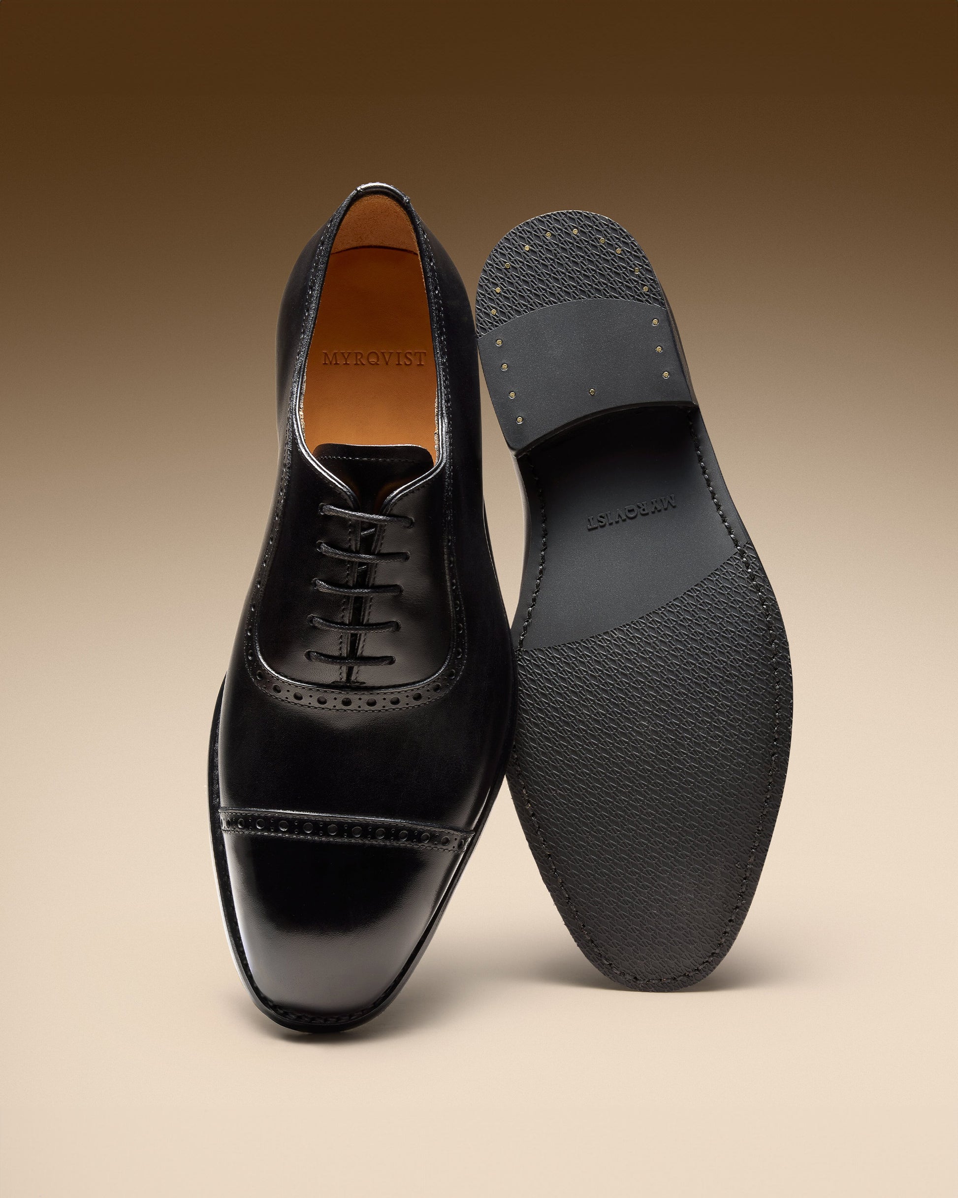 A pair of Skytteholm II – Black Calf oxfords, one showing the cap-toe upper and the other the textured rubber sole.