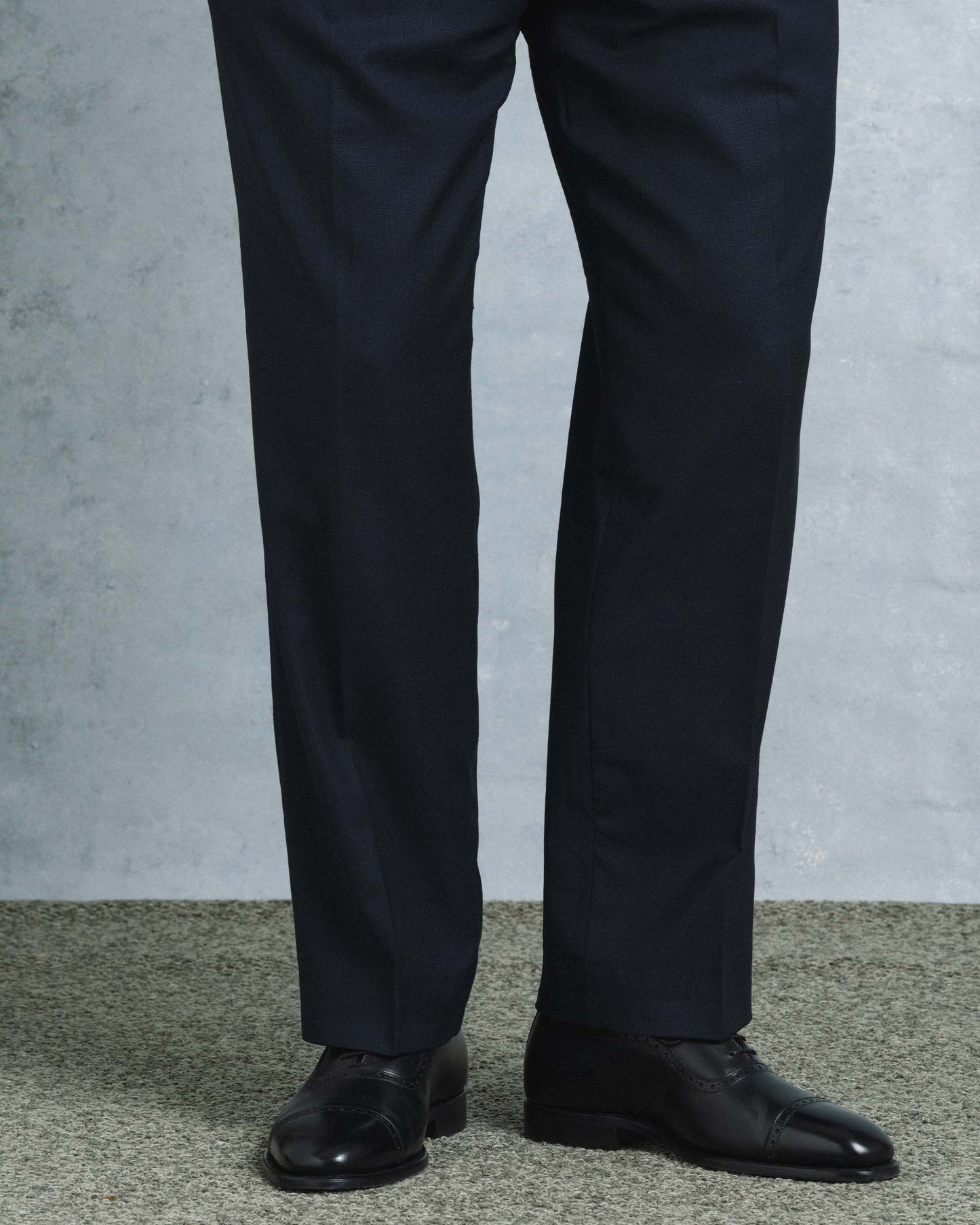 Skytteholm II in black calf worn with tailored dark dress trousers, highlighting the Oxford shoe's polished finish, closed lacing, and subtle brogue cap toe in a formal setting.