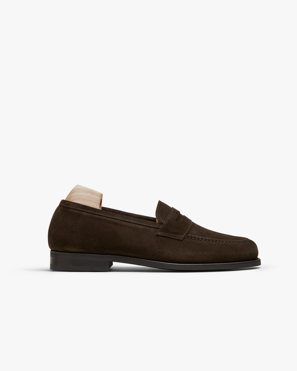 Stenhammar II in dark brown suede features a softly rounded silhouette with an apron front, subtle stitching, and a rich suede texture, shown in profile with a wooden shoe tree inserted.