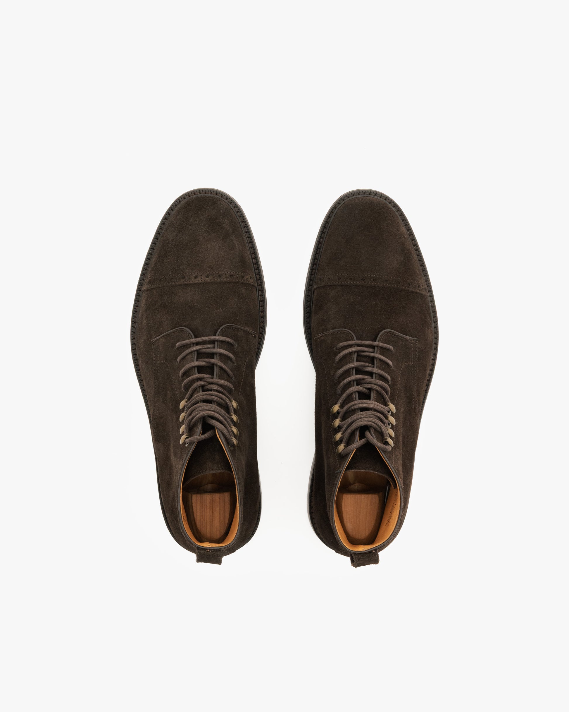 Top-down view of a pair of Tjärnö II – Dark Brown Suede cap-toe boots with shoe trees inside.
