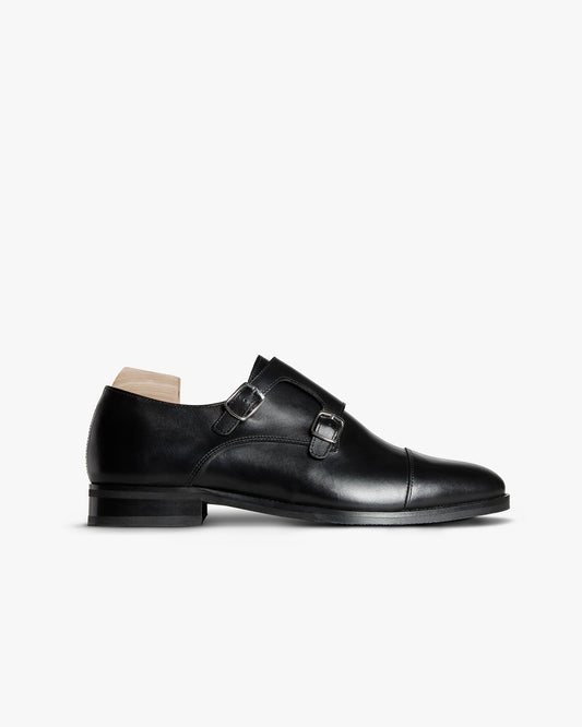 Ålsten II – Black Calf double monk strap shoe in side profile with silver buckles and a wooden shoe tree.