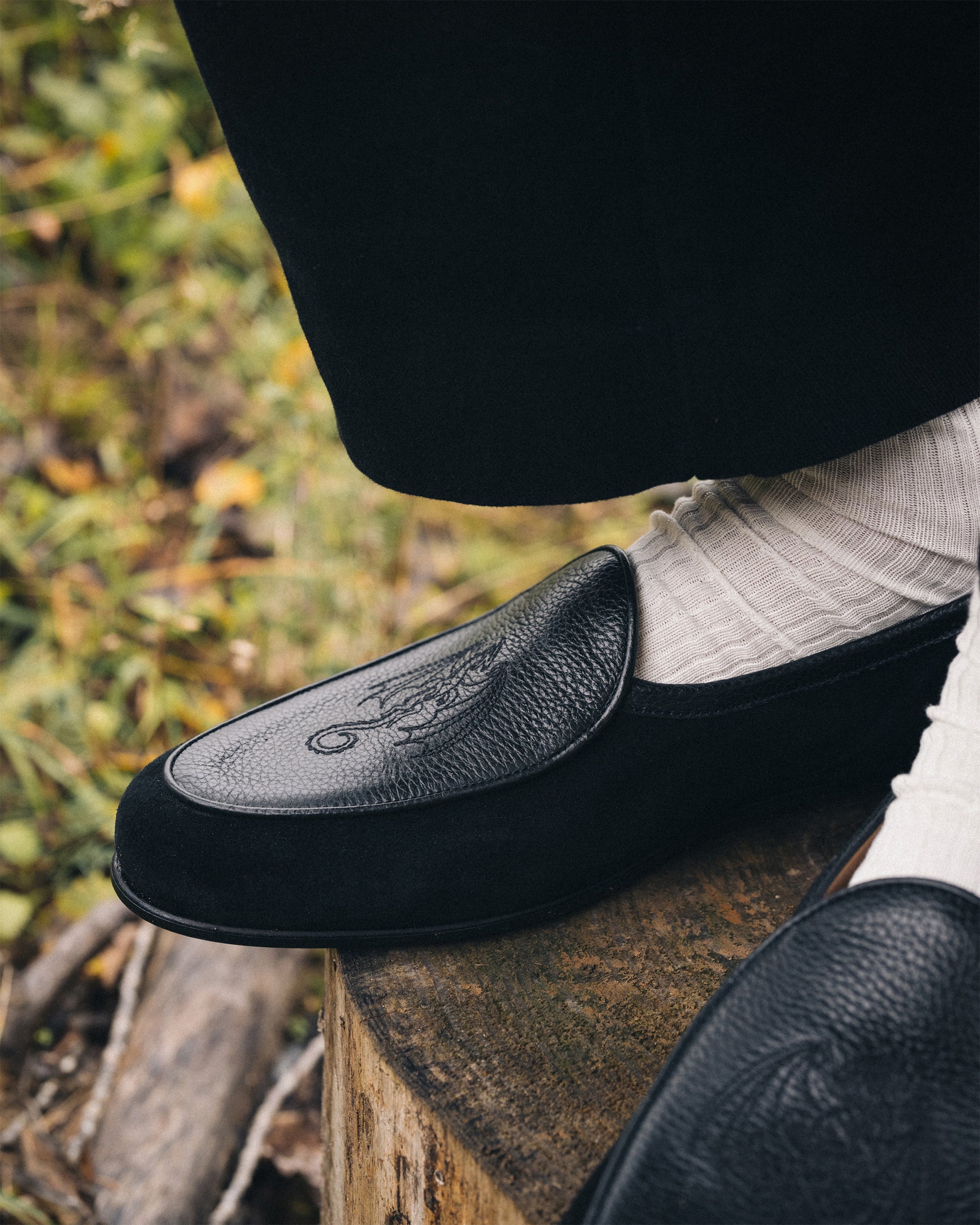 Close-up of Ängby – Fares Edition loafer, worn with light socks and black trousers, showing the dragon embroidery.