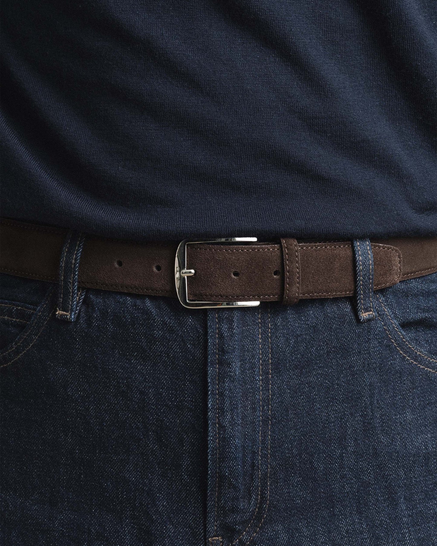 Dark brown suede belt with a square silver buckle, styled with dark denim jeans and a navy shirt for a refined, casual look.