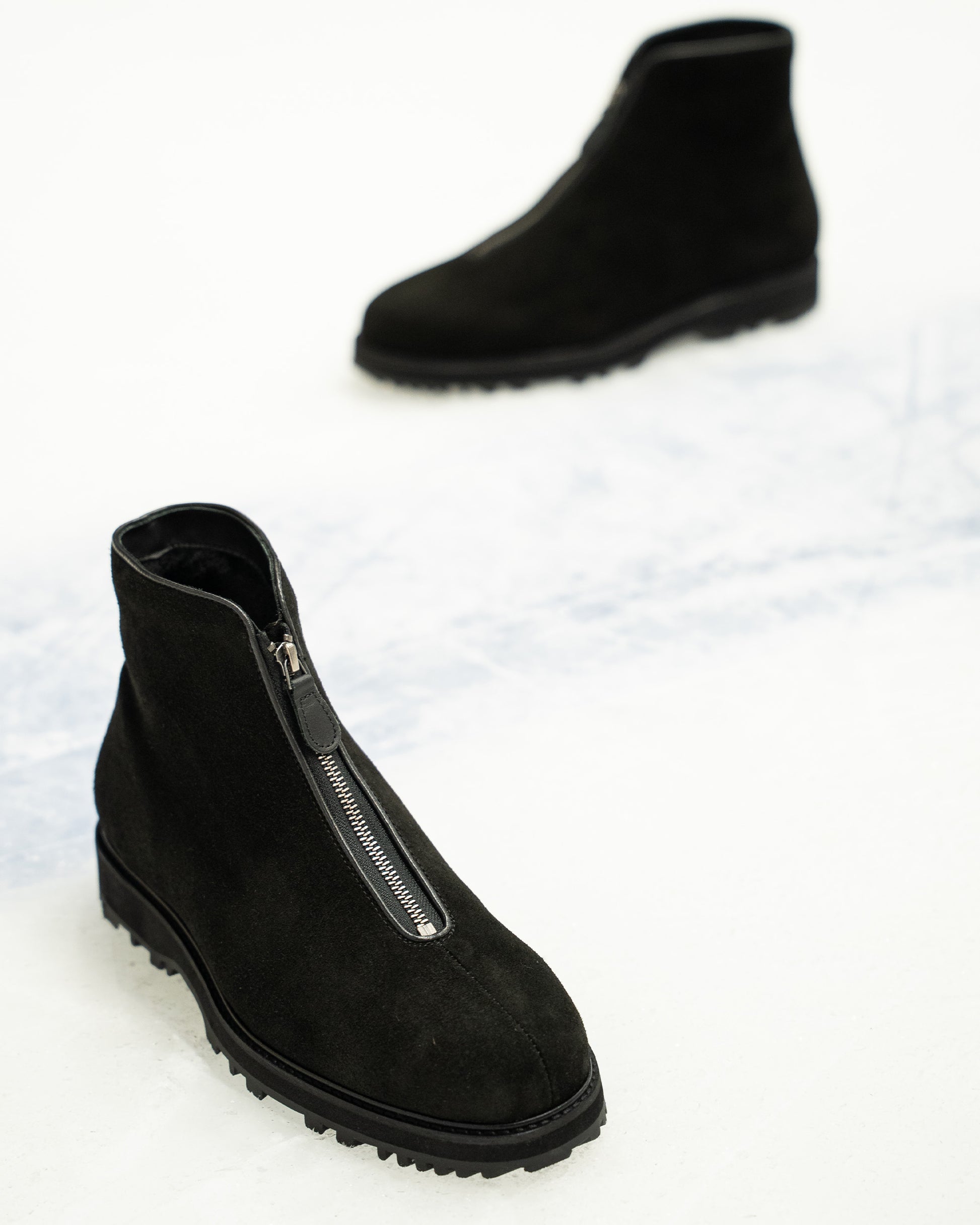 Funäs in black suede boots displayed on a light surface, featuring water-repellent suede, a central zip closure, and a rugged Explorer sole designed for winter versatility.