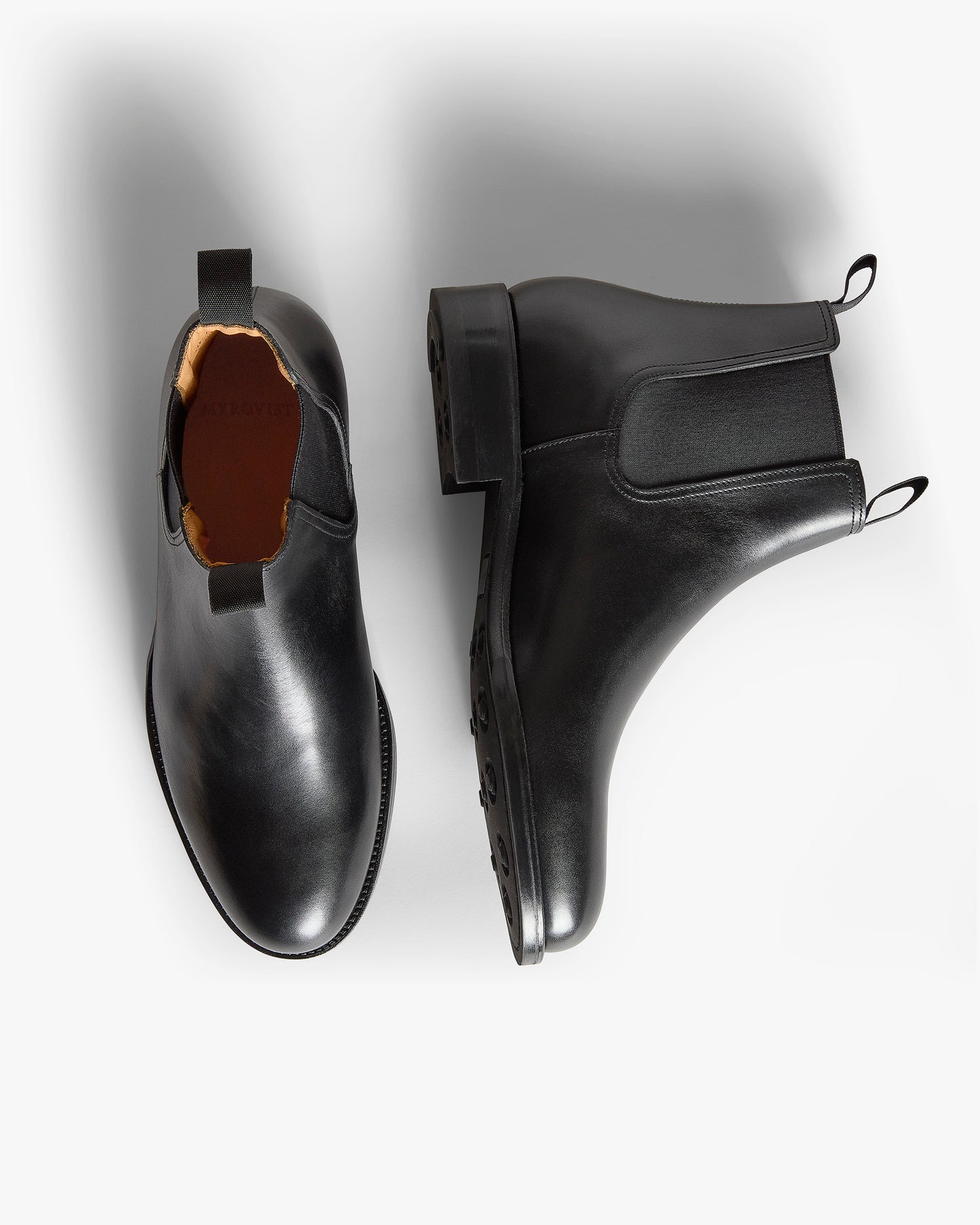 Elfvik II – Black Calf Chelsea boots shown with one shoe viewed from above and one showing the sole.