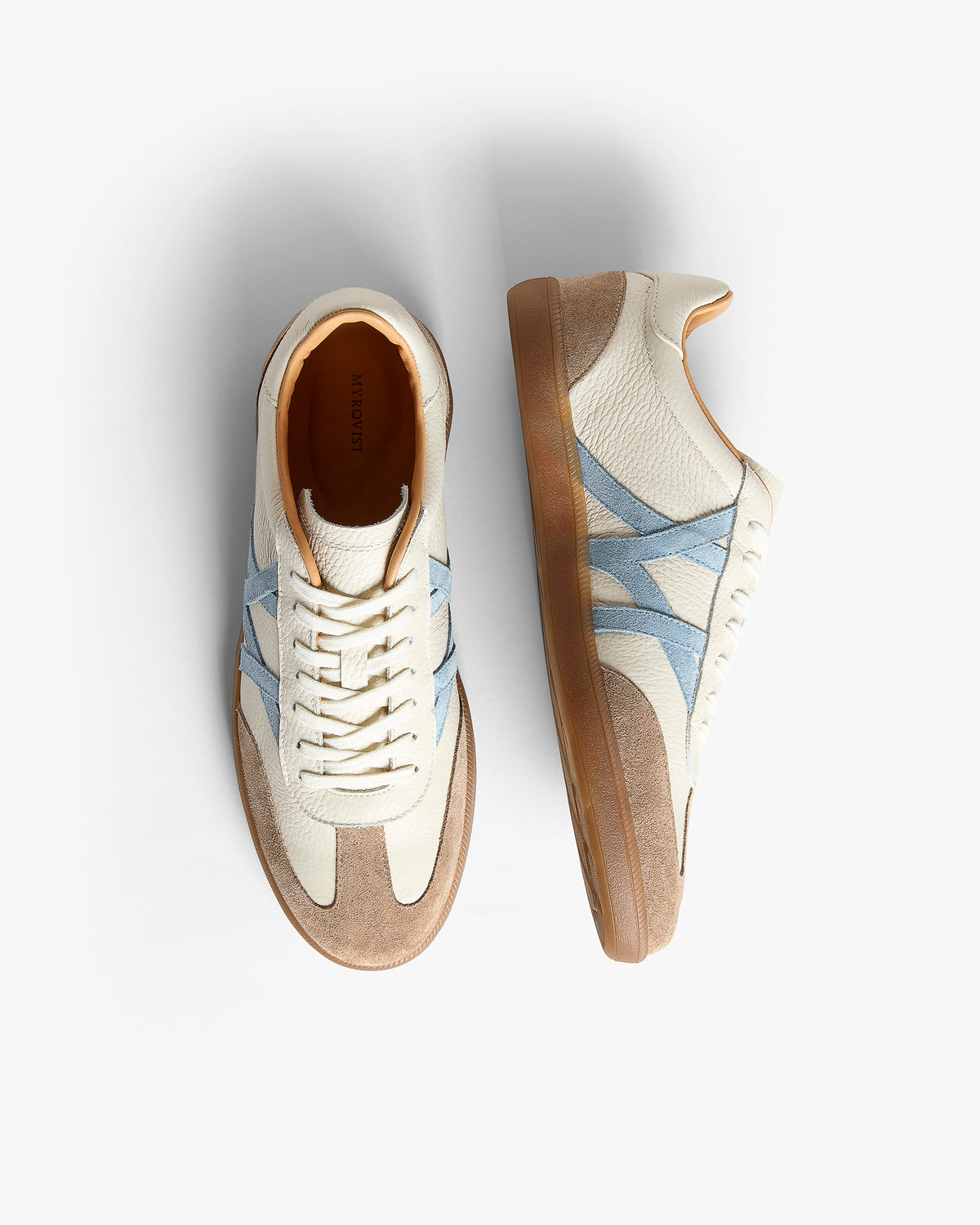 Högalid – White Natural Grain sneakers in soft tumbled leather, displayed from above and side to show the blue M-pattern.