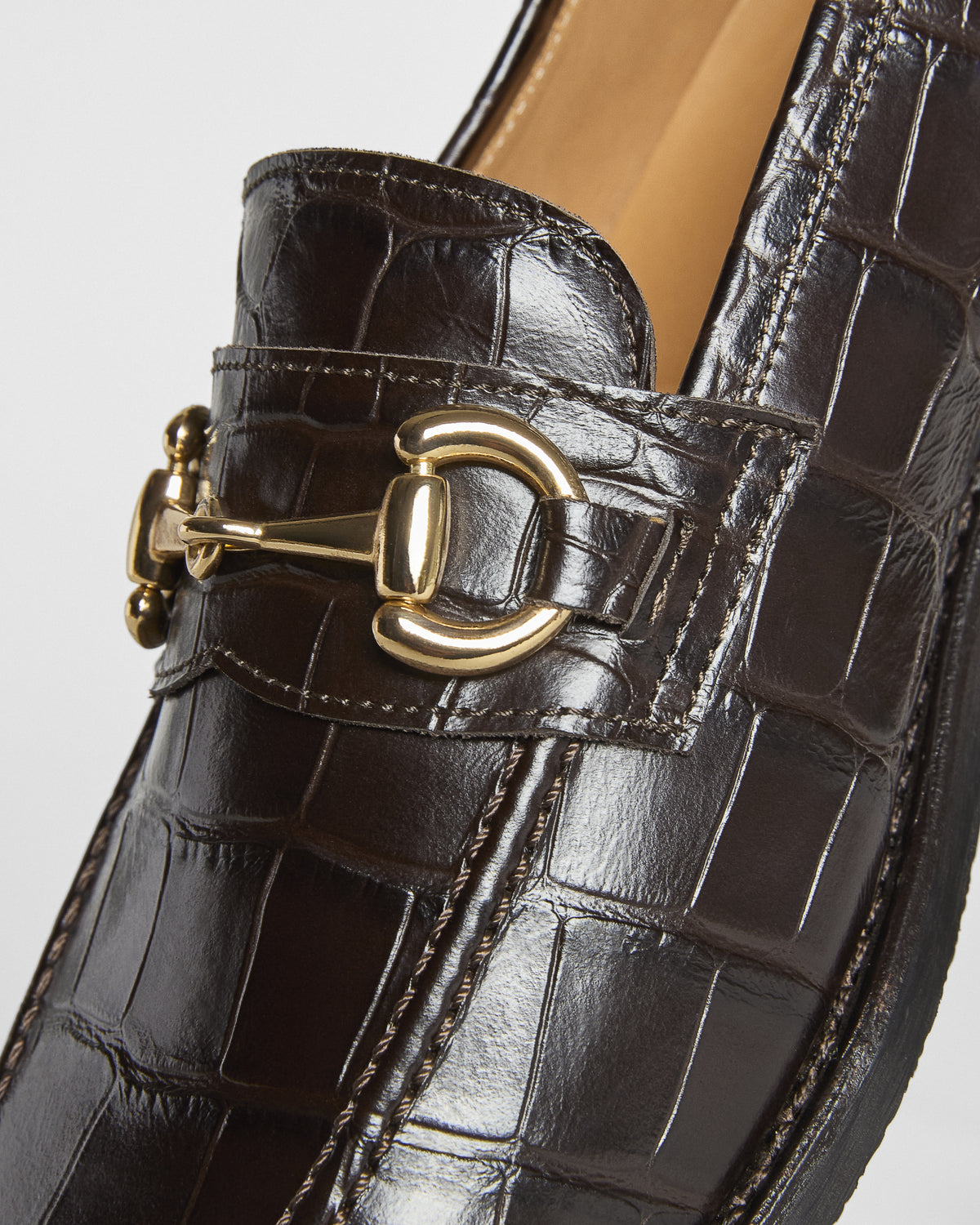 Dark brown embossed croco leather loafer featuring a polished gold-toned horsebit detail across the front.