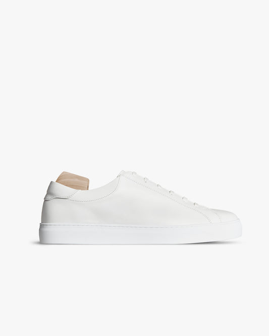 Oaxen – White Calf sneaker in smooth white leather shown in side profile with a wooden shoe tree against a white background.